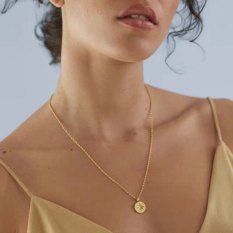 Woman wearing silver compass star necklace with the north star coin pendant resting at her collarbone