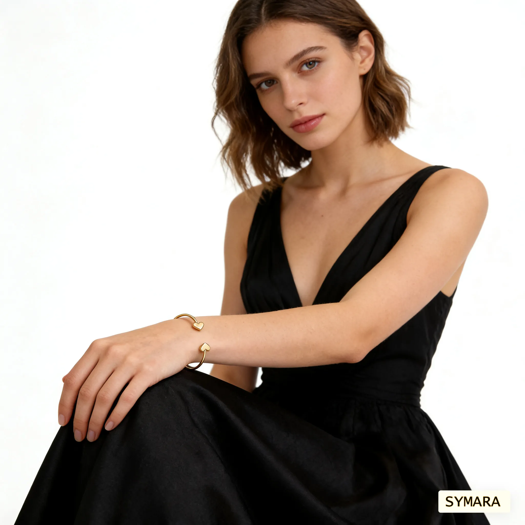 Woman wearing SYMARA adjustable heart open cuff bracelet in 18K gold, layered with other bracelets