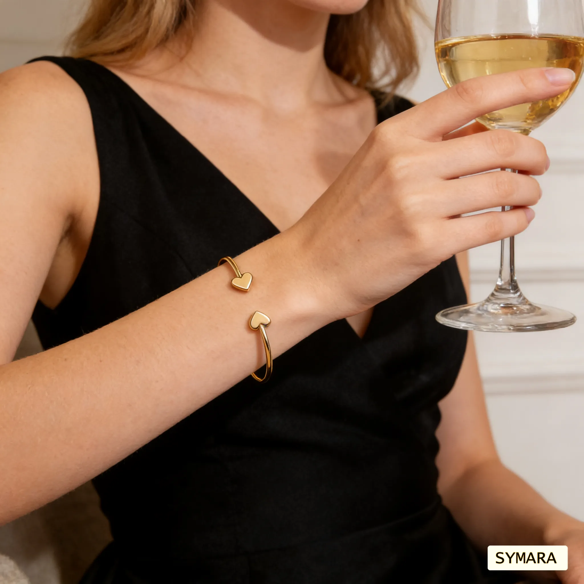 Woman wearing SYMARA adjustable heart open cuff bracelet in 18K gold, layered with other bracelets