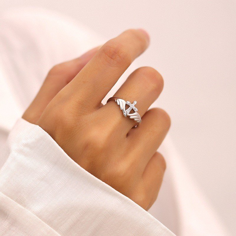 Model wearing angel wing cross ring on index finger, women's personality street fashion copper ring