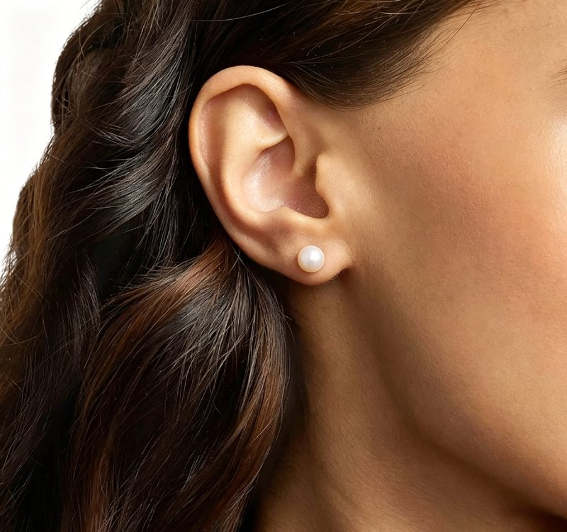model-wearing-freshwater-pearl-stud-earrings-18k-gold-1 Woman wearing simple 10-12mm freshwater cultured pearl stud earrings for everyday wear
