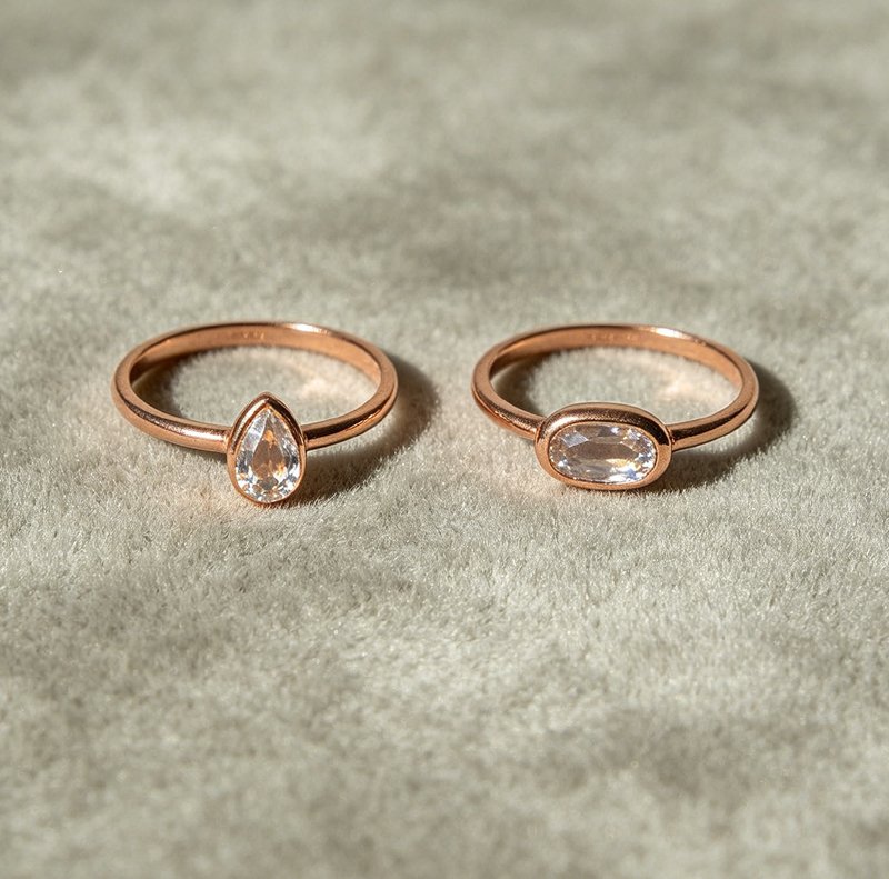 Two toi et moi rings laid flat showing round with pear cut and oval with cushion cut

