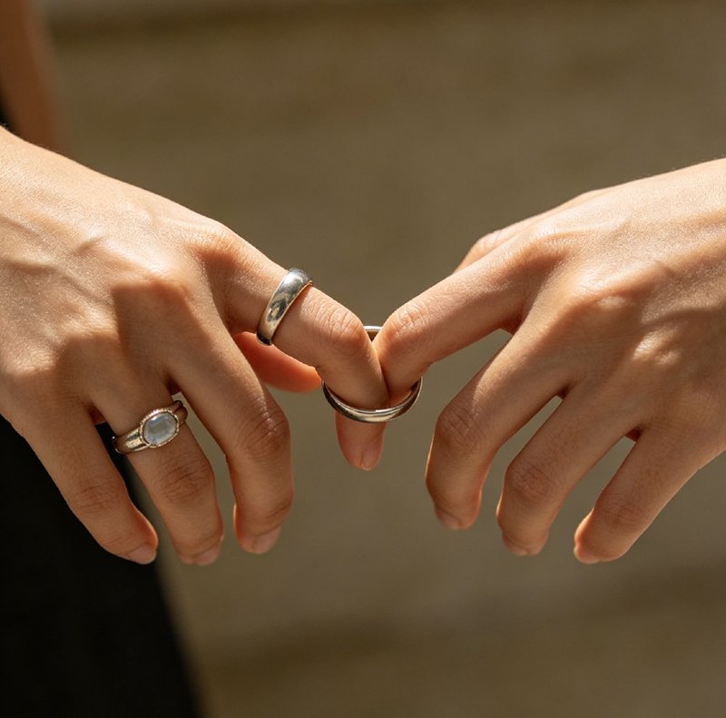 Two hands gently touching, one wearing a two-stone toi et moi ring