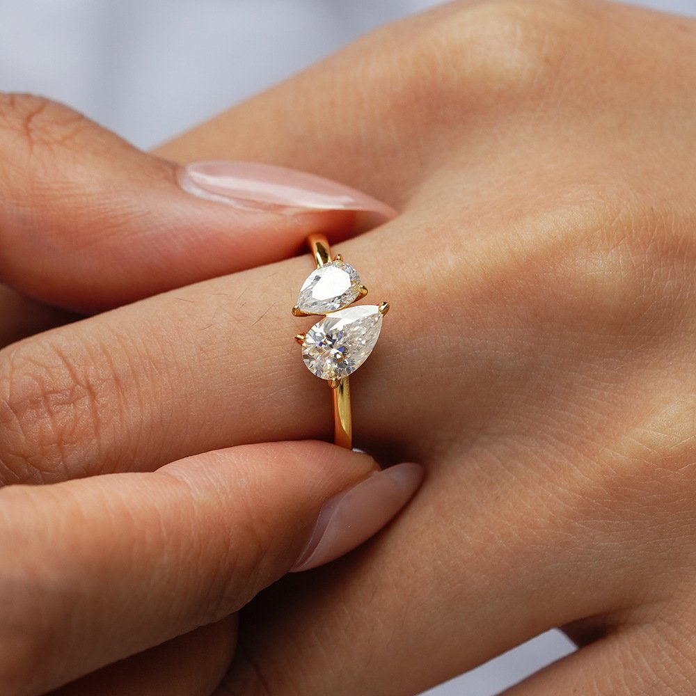 woman-wearing-toi-et-moi-moissanite-ring Woman wearing a toi et moi moissanite ring on her finger, showing the two stone design