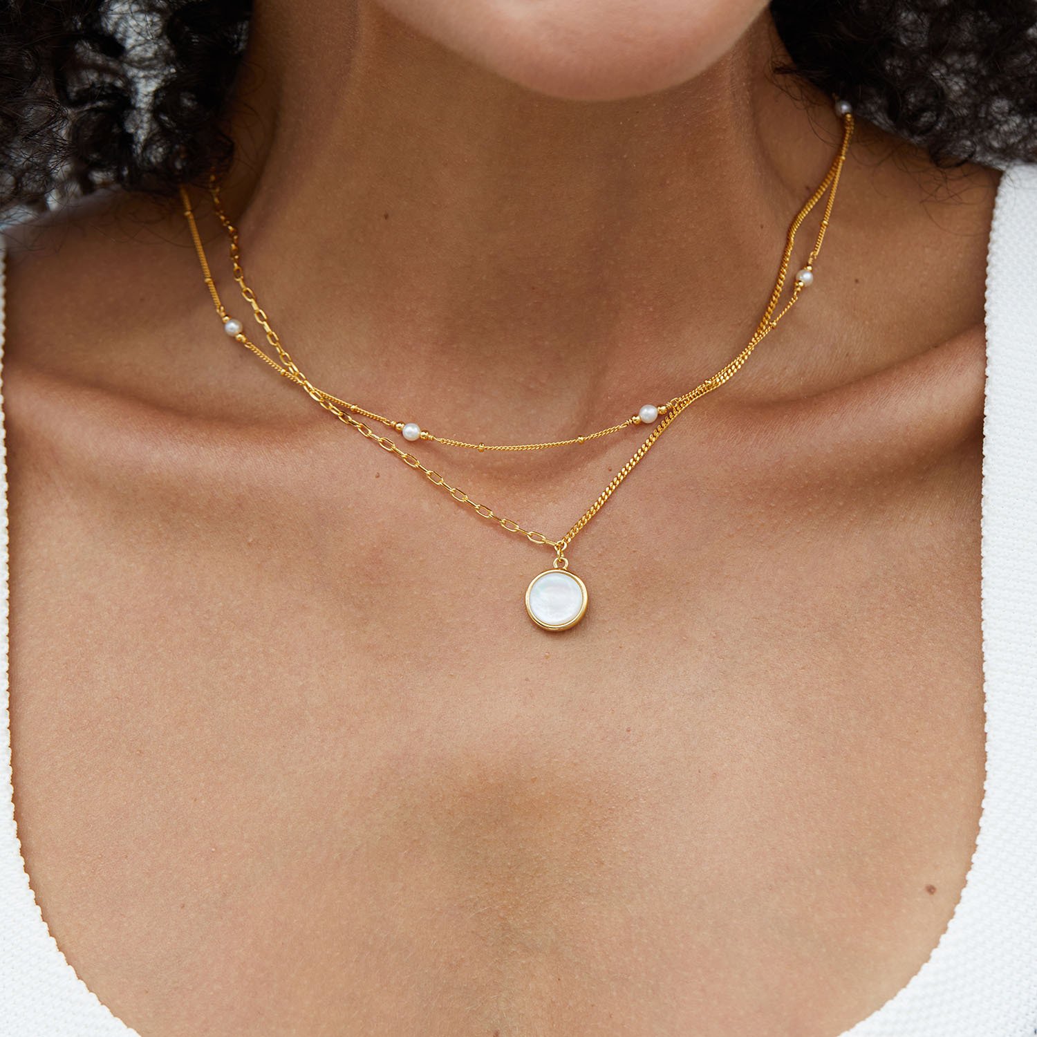Close-up of mother of pearl necklace on a woman's collarbone. Iridescent sheen adds a subtle glow to any neckline.