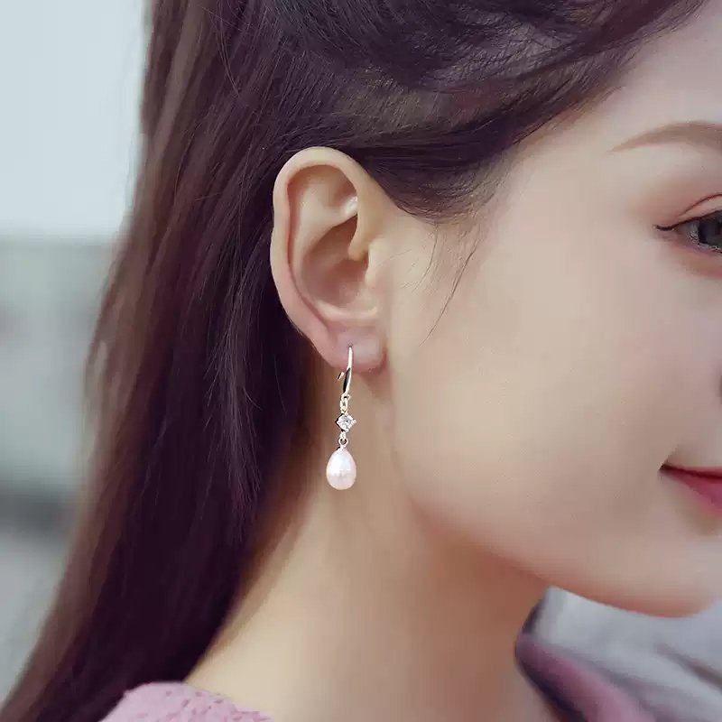 Outdoor lifestyle photo of female styling zircon embellished freshwater pearl drop earrings for casual daily look