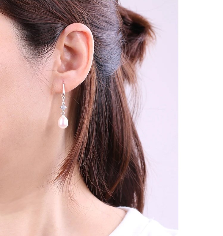 Outdoor lifestyle photo of female styling zircon embellished freshwater pearl drop earrings for casual daily look