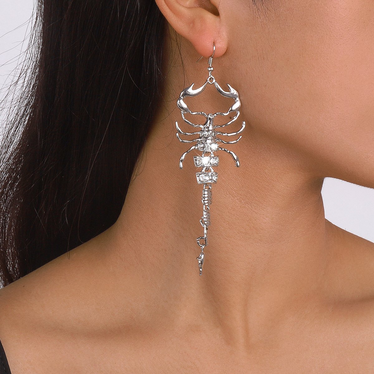 Model wearing gold scorpion novelty earrings with rhinestones, bold gothic look