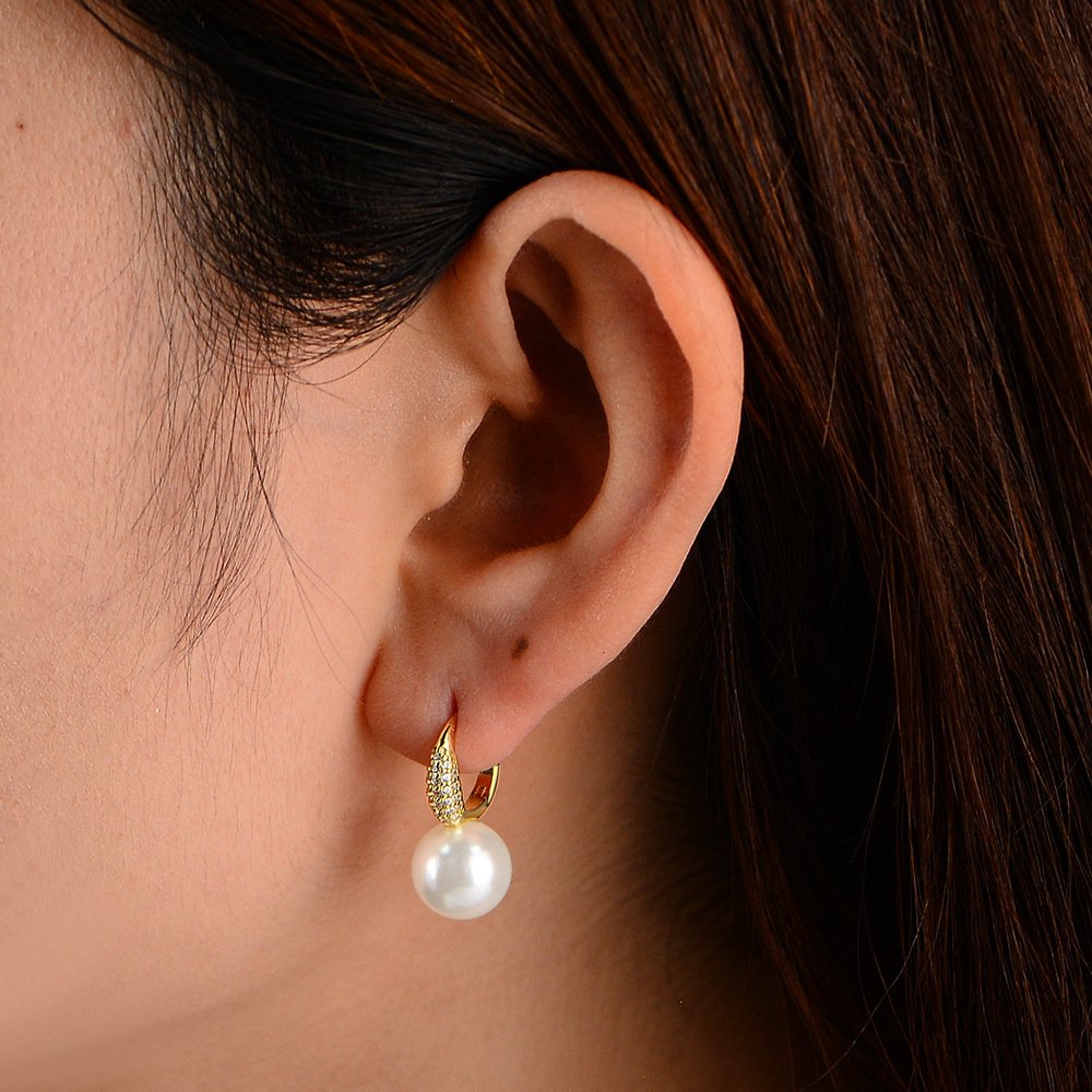 Model wearing SYMARA gold tone pearl huggie earrings daily style