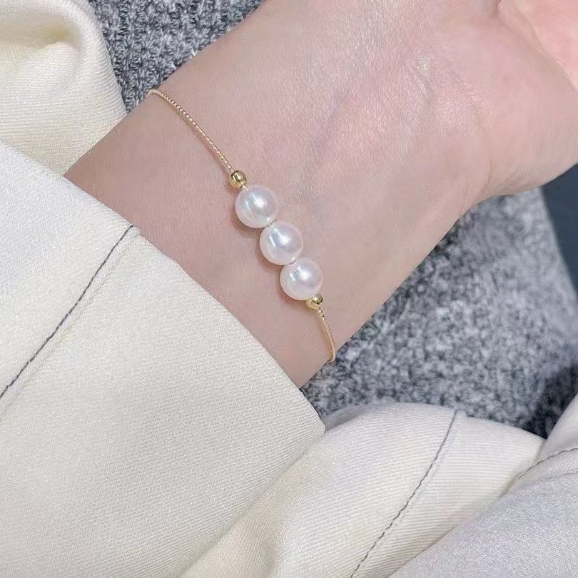 Stack styling of slim 18K gold Akoya pearl bracelet, minimalist white pearl wrist jewelry
