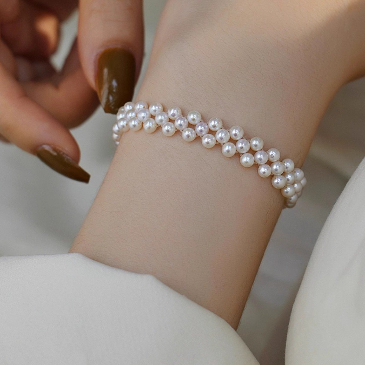 Elegant woman wearing gold-tone hand-woven freshwater pearl bracelet on wrist, 3-4mm round pearls with S925 sterling silver, sophisticated everyday pearl jewelry.