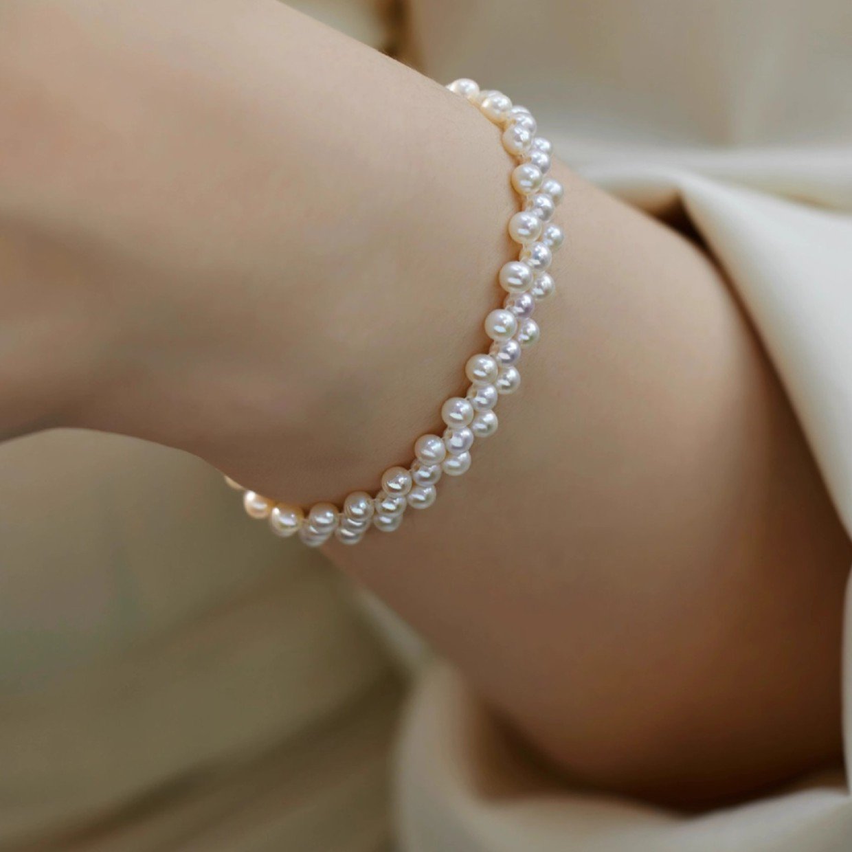 Elegant woman wearing gold-tone hand-woven freshwater pearl bracelet on wrist, 3-4mm round pearls with S925 sterling silver, sophisticated everyday pearl jewelry.