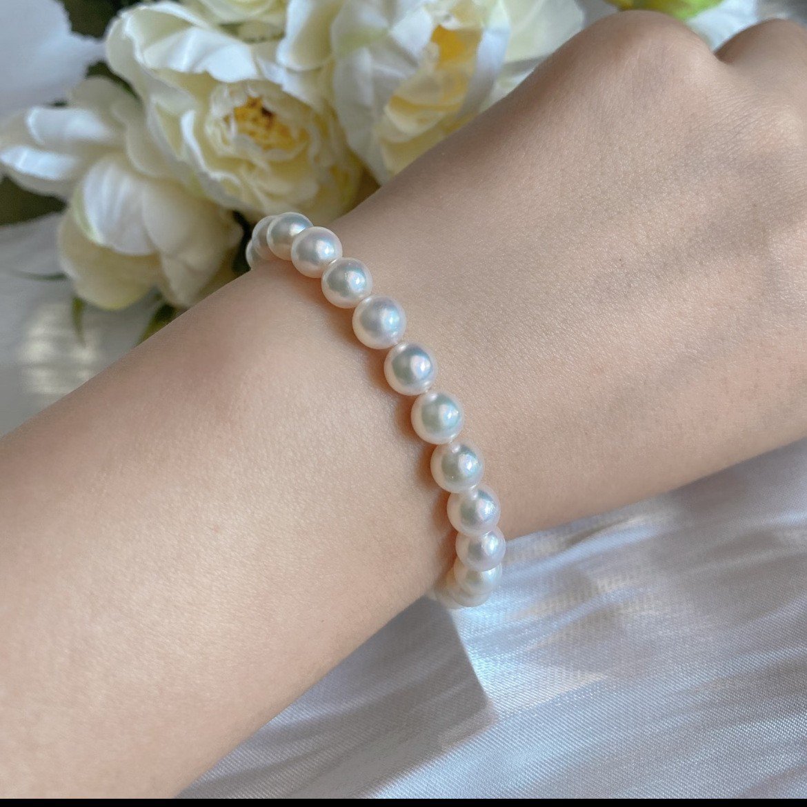 Elegant women wearing classic 7‑8mm natural white Akoya seawater pearl bracelet on wrist, S925 silver filigree clasp luxury pearl wrist jewelry for daily and office styling